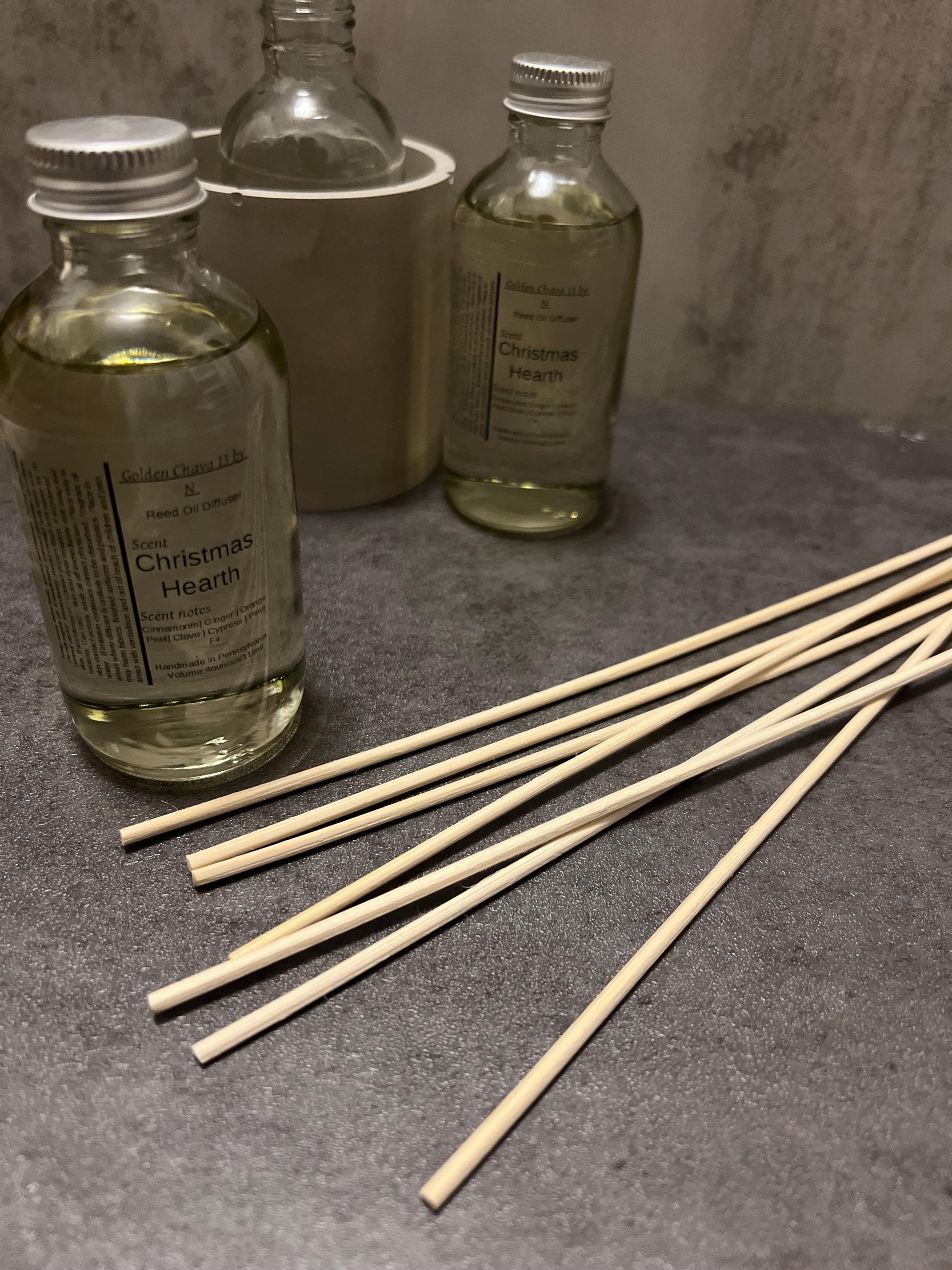 4 oz reed diffuser with glass bottle labeled Christmas Hearth, flower and spiral reed plus straight wooden reeds.