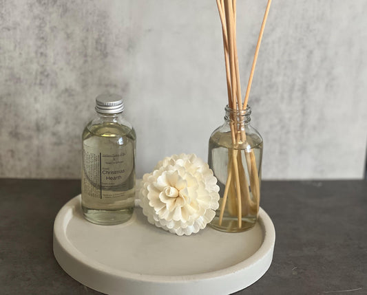4 oz Reed Diffuser set: glass bottle of fragrant oil, flower/spiral reed, and three straight wooden reeds on a tray.
